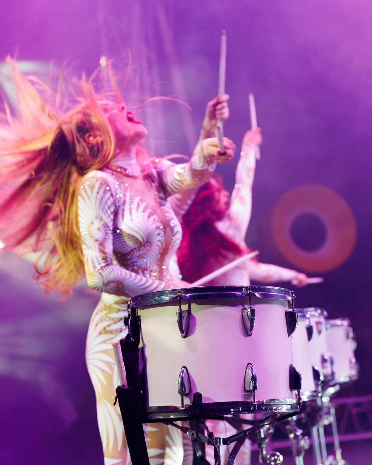 A drummer mid-hit with sticks raised