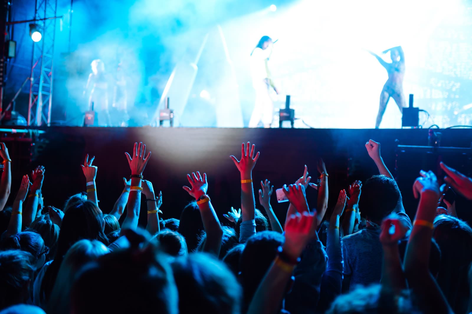 A crowd with raised hands in front of a lit stage