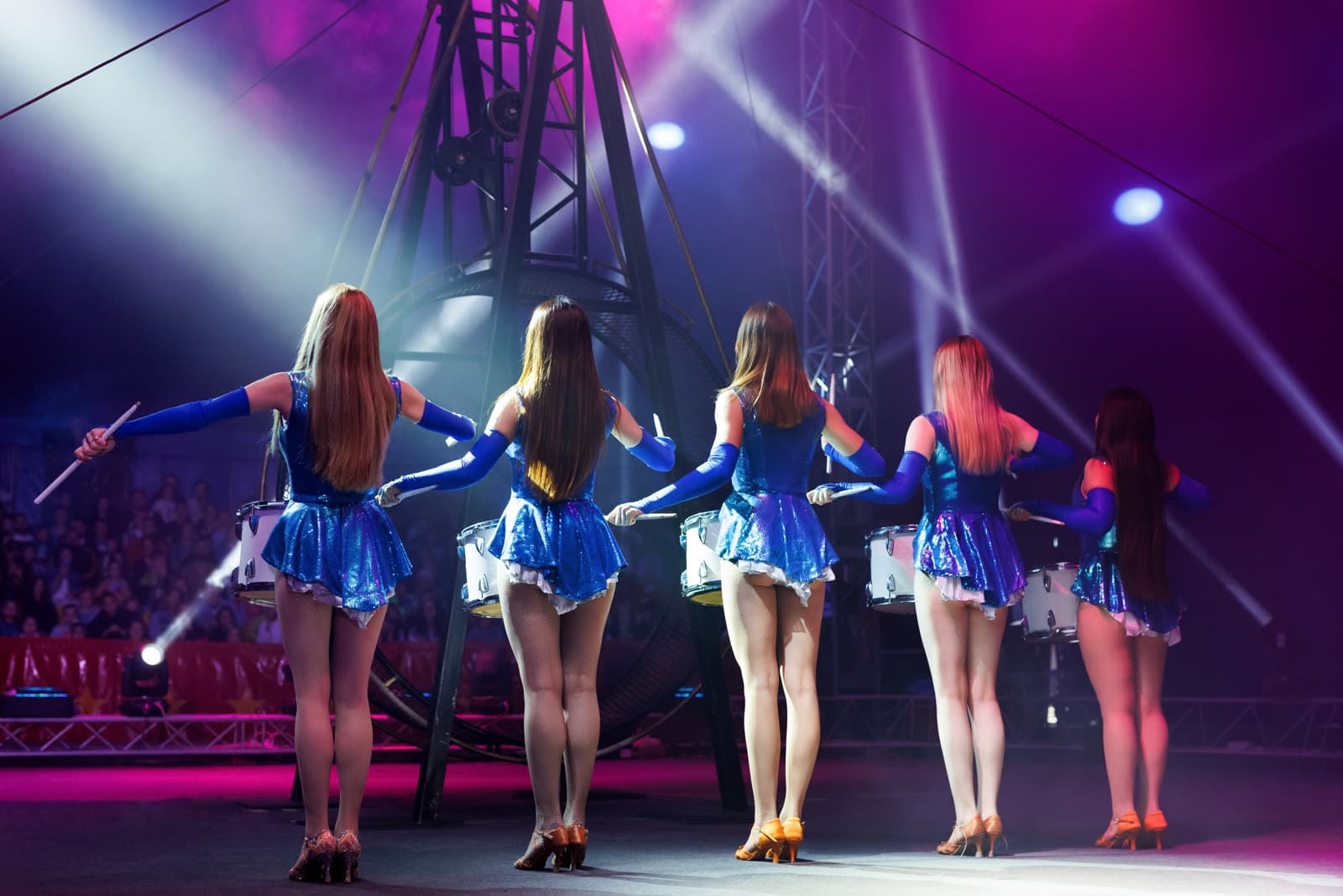 Performers in sequined dresses under a spotlight