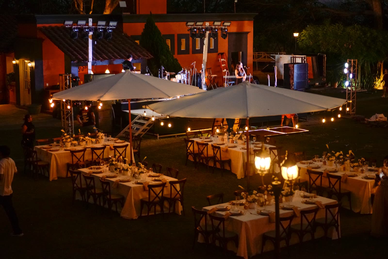 Long tables set for an evening event under string lights