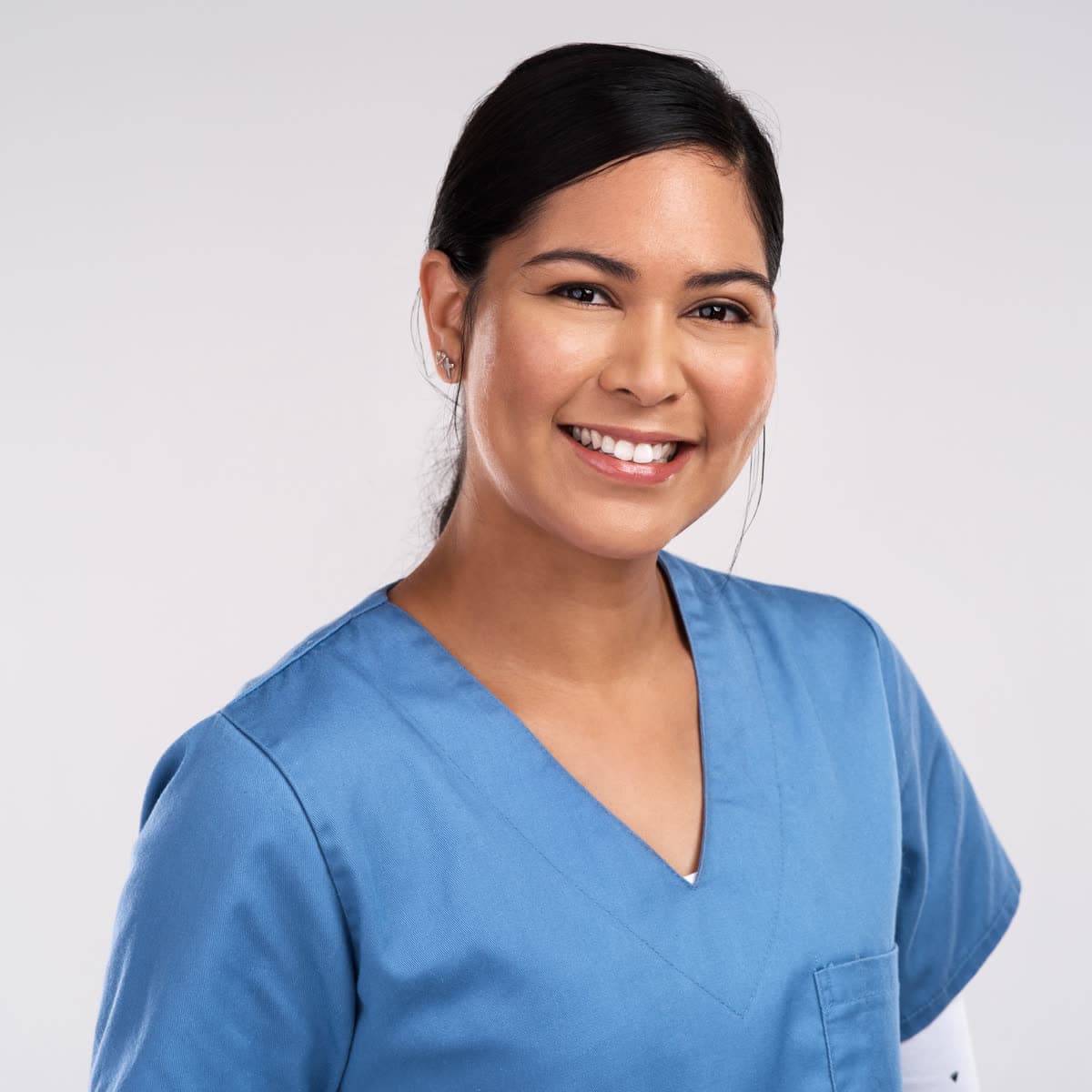 A smiling hygienist in blue scrubs