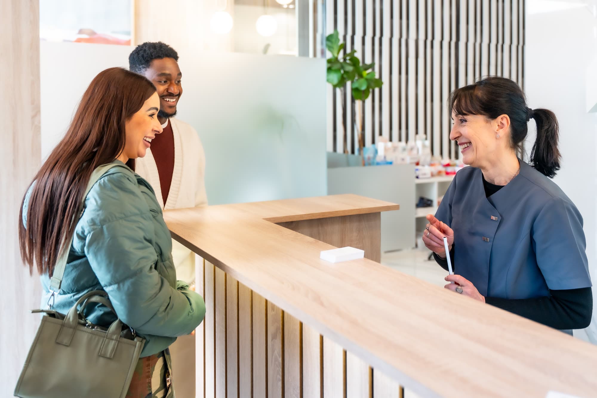 A patient checking in at a bright reception desk with a smiling receptionist