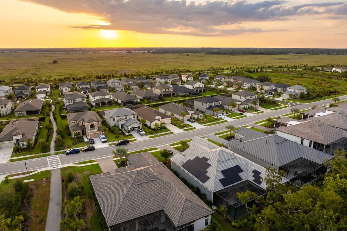 Aerial view of a neighborhood at sunset with open land beyond