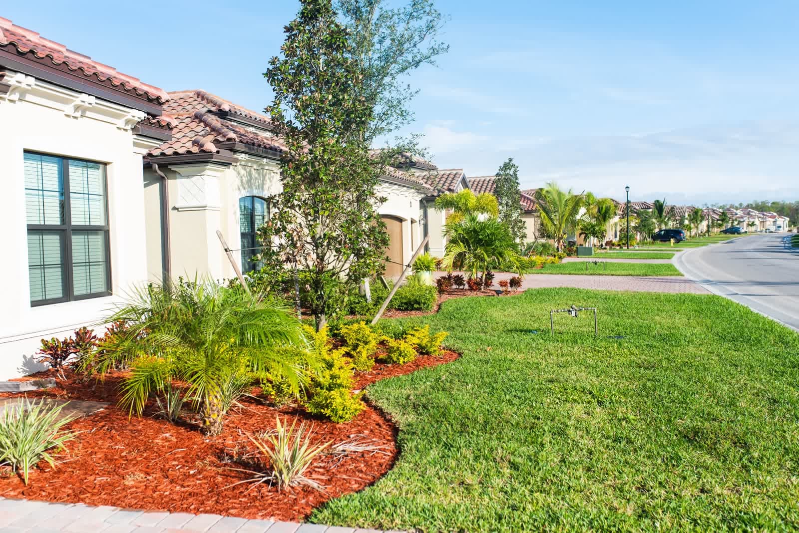 A tile-roofed home with landscaped beds on a quiet golf community street