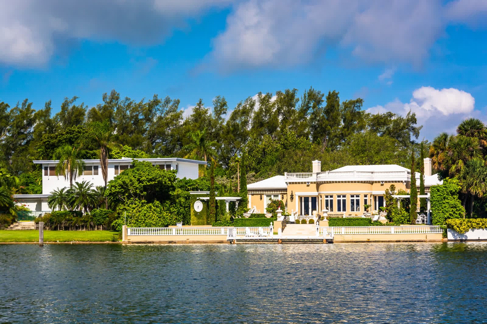 Cream-colored waterfront homes behind palm trees across a calm canal