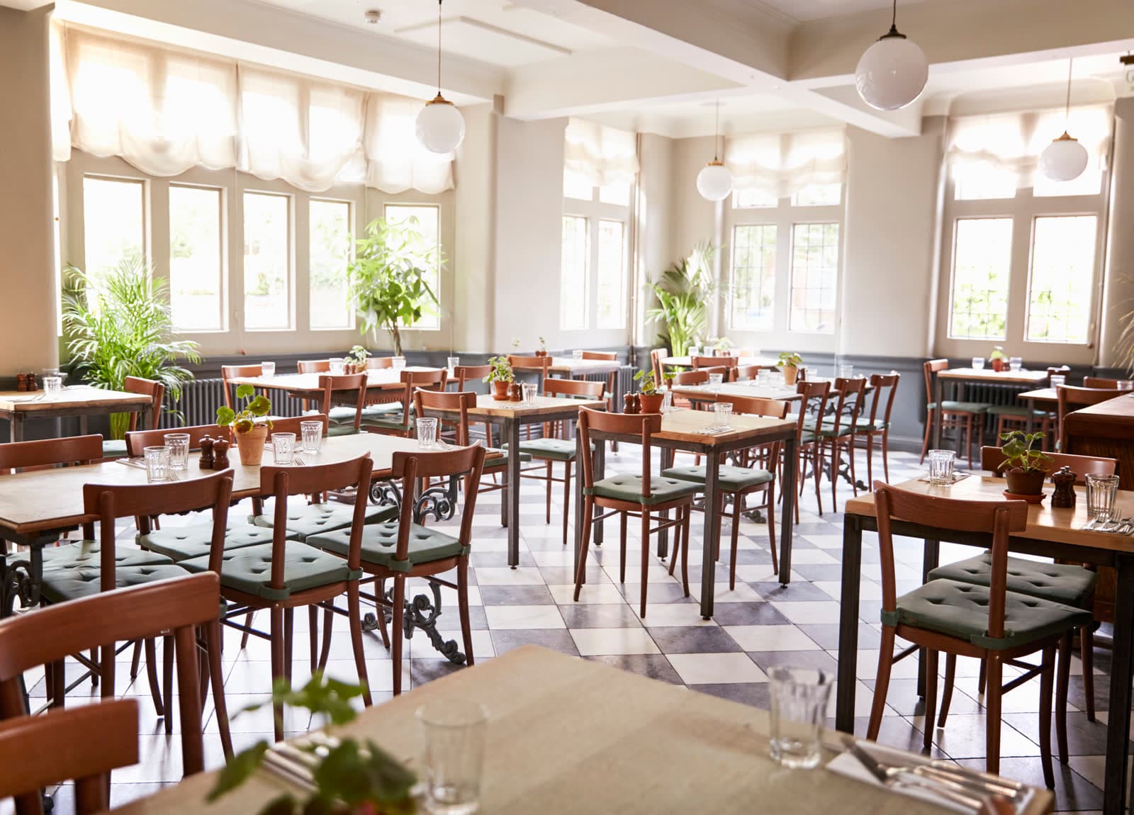 A bright dining room with wooden tables and tall windows
