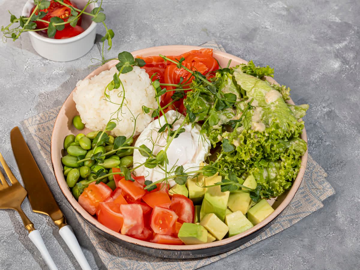 A bowl of rice, salmon, avocado, edamame and a poached egg