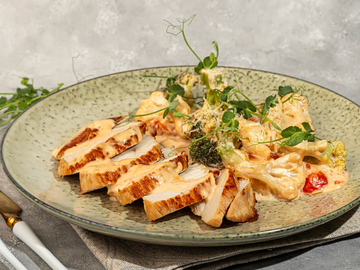 Sliced grilled chicken in a creamy sauce with microgreens