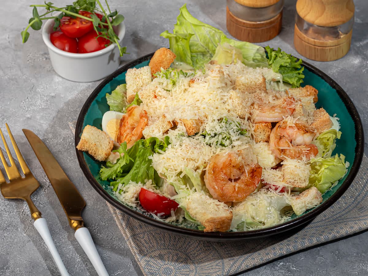 A shrimp salad with croutons and grated cheese